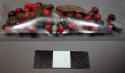 Ornaments, seeds, some red and black, others tubular buff, resin adhering