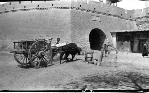 Man with ox and cart near arch