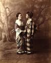 Two young Japanese women in traditional dress holding hands