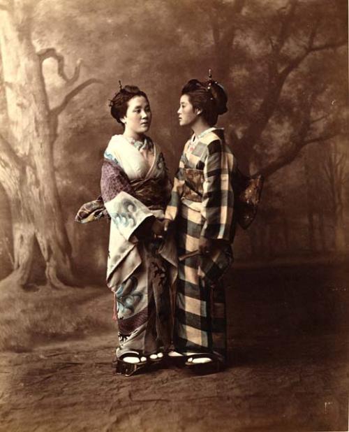 Two young Japanese women in traditional dress holding hands