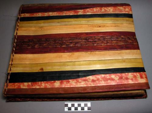 Fibre sleeping mat of red, yellow, orange and black strips