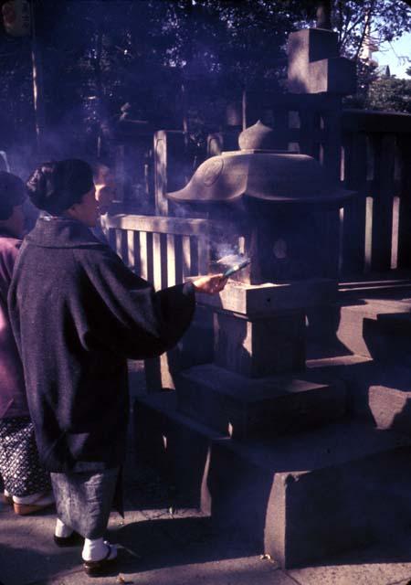 Tokyo, Sengakuji Shrine, woman lighting incense