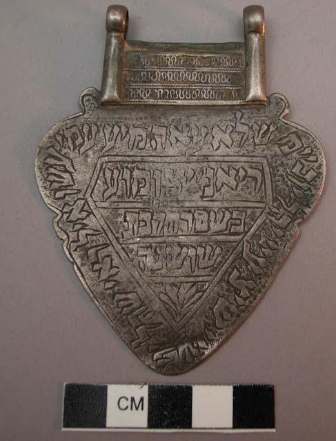 Metal pectoral with hebrew inscription on one side; two loops at the +