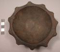 Carved dark-colored wood bowl with scalloped edges, rim of base pierced for hang