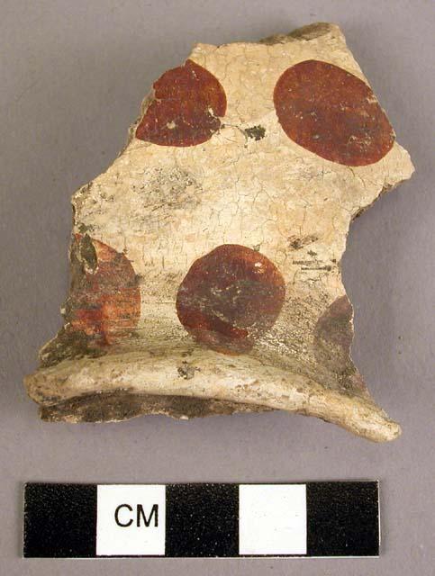 Ceramic body sherd, flared base or rim, red on cream large dots, crackled, worn