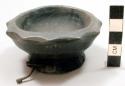 Small dark colored carved wooden bowl with scalloped edges, base rim pierced wit