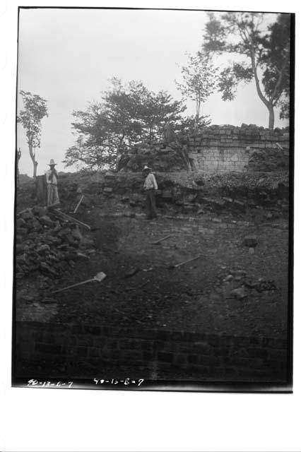 Man pointing to terrace level of plinth wall remnant