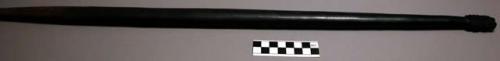 Baton or staff, made of black wood, pointed at one end; small carved decoration