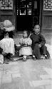 Woman sitting with children by doorway