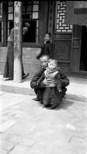 Man posing with child in courtyard