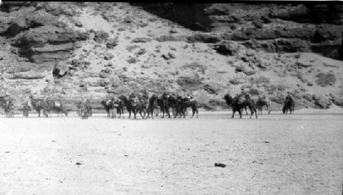 People riding camels by mountain