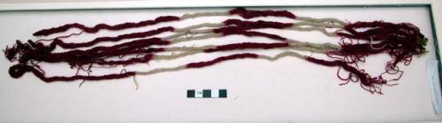 Organic, twisted fiber string, red and white alternating bands, attached at end