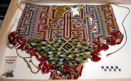 Skirt of glass beads strung on fibre, red and white cotton cloth fringe