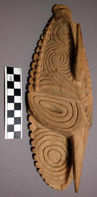 White wooden mask with incised circular and spiral designs. 11.5" l.