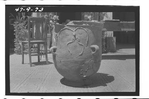 Large pottery burial urn with crude human face appliqued on ext. wall.