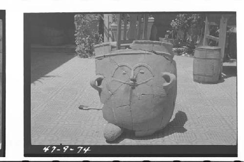 Large pottery burial urn with crude human face appliqued on ext. wall.