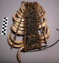 Breast ornament composed of vertical arrangement of boar tusks and +