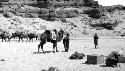 People and camels in desert by mountain