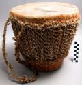Drum, tapered wood body, animal skin covering, leather strip binding, strap