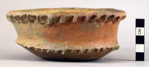 Earthenware bowl with carvings around rim and base, glazed in interior