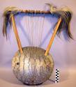 String instrument, wood body, reptile skin head, 8 strings, crossbar with animal