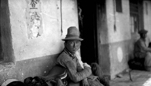 Man with hat sitting outside building