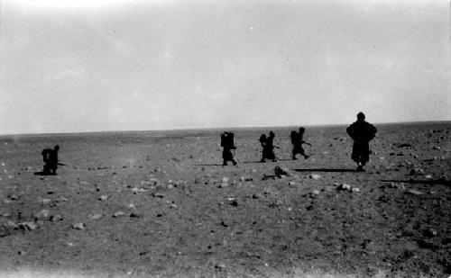 People with packs walking in desert