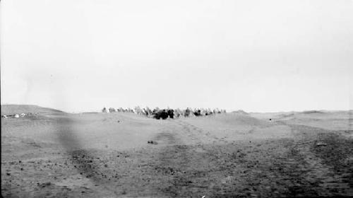 People with camels and equipment in desert