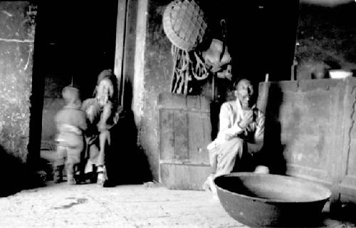 Man sitting with child, another man sitting by large bowl