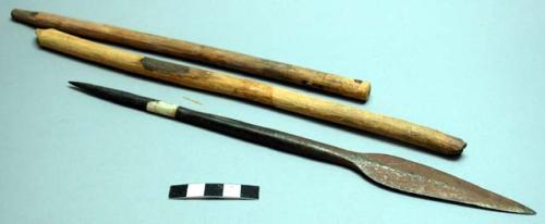 Two wooden sticks, stripped of their bark; 1 metal spear point