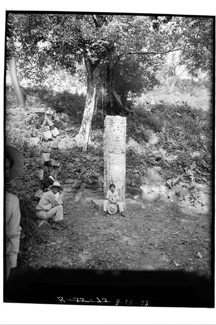 People sitting around Stela P after its straightening