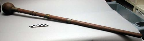 Club of dark wood with spherical head and four bands of woven copper