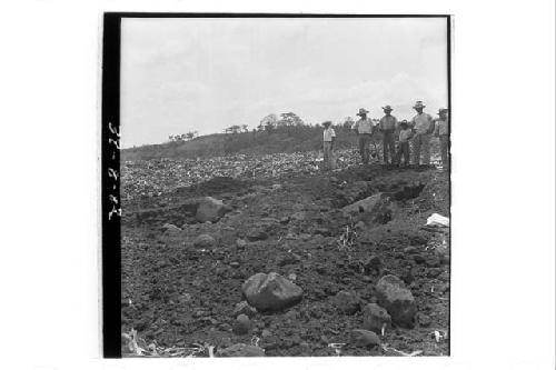 Hillside view of laborers excavating stela