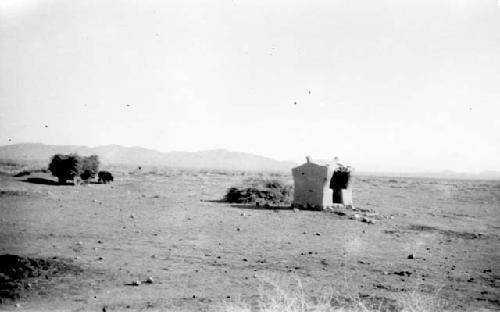 Small hut in desert, mountains in distance