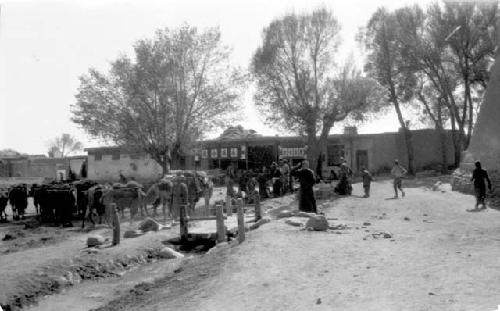 People and camels by buildings