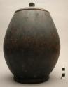 Wooden jar, carved, with lid, bulbous body, leather strap attached to square lug