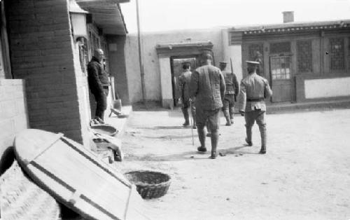 Men in uniforms walking by buildings