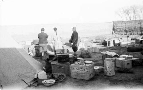 People standing outside tent, many boxes