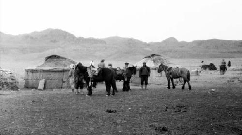 People and ponies by huts in desert