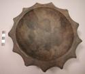 Dark colored carved wooden bowl with scalloped edges, rim pierced for hanging. G