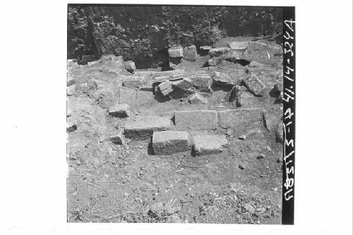 Oblique downward panorama of fallen, squared wall stones of N. exterior wall.  F