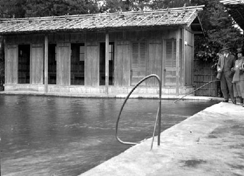 People standing near pool of water, building in background
