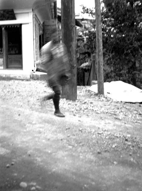 Man running on dirt road past white building