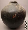 Jar, ceramic, dark brown glaze, flat base, round body, constricted rim, pitted