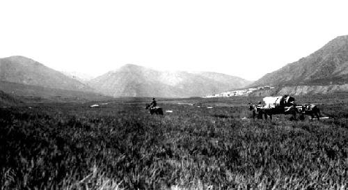 People on horseback and wagon moving through field