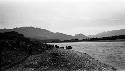 Boats at river's edge, mountains in background