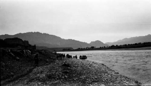 Boats at river's edge, mountains in background