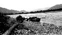 Boat moored at river edge, people and horses with wagon on shore