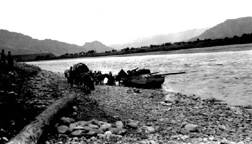 Boat moored at river edge, people and horses with wagon on shore