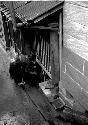 Man bending over baskets under awning in front of building